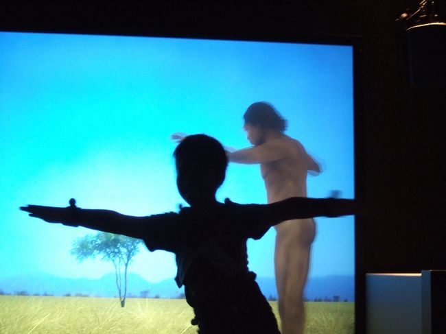 センサーの動きを感知して、スクリーンにうつっている原始人が動く！　右に行くと進化します。