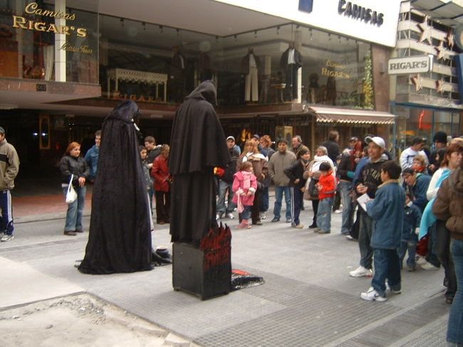 ブエノスアイレスの下町歓楽街ラヴァージェ通りで不動の<br />ままで立っている人間人形､黒い魔女姿を興味津々で見つめている人達．