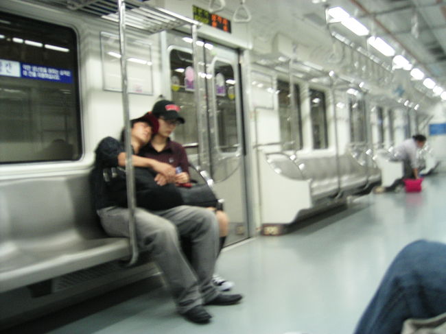 地下鉄車内はこんな感じ。<br />いすが硬い硬い。<br />中吊り広告なくて液晶の広告です。<br />