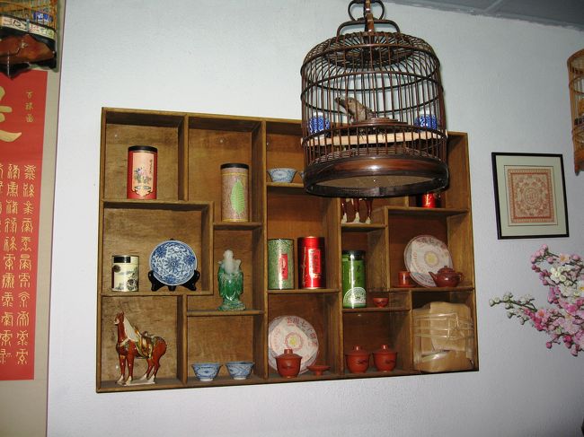 作り付けの壁の棚には、皿や唐三彩風の馬の焼物、茶道具などが展示されています。鳥篭も中国ならではの光景です。
