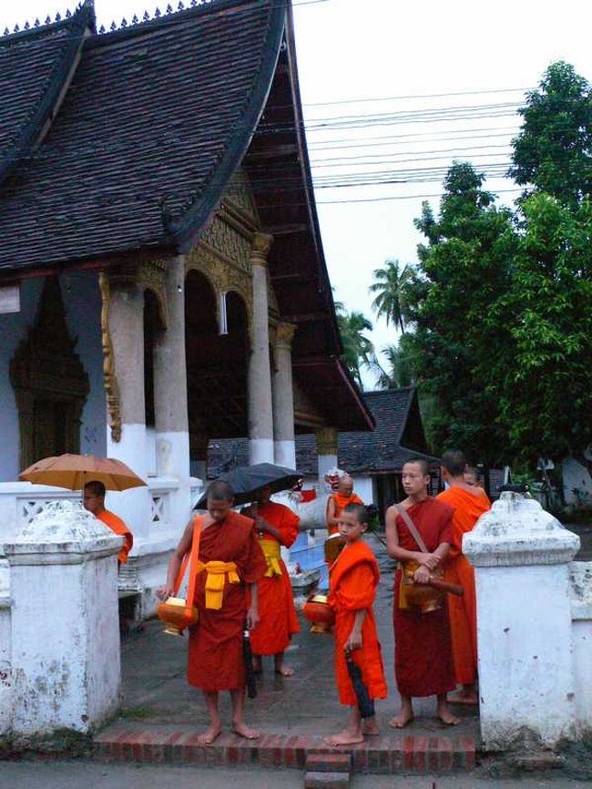 寺の入り口で出待ちをする托鉢僧。<br />雨が少し降っていたので傘をさしている僧も。