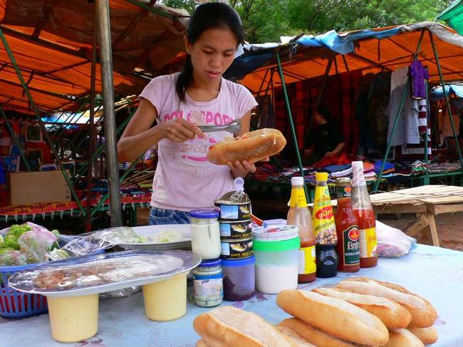 バザールでサンドイッチを売るお姉さん。<br /><br />ラオスのフランスパンもおいしいと有名なのでこの日のランチはサンドイッチ。<br /><br />野菜、ハム、鶏肉をはさんだ後は、チリソースをかけて。