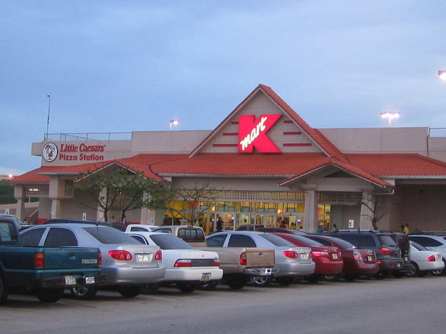 【とりあえず、スーパー☆】<br />今回の旅でひとつ楽しみにしていたのが、地元のスーパーへ行くこと。<br />これはどの国に行っても欠かせないことですが、特に今回は宿泊先のすぐ近くに大きなスーパー「Kマート」があったので、まず一番最初にチェックしてきました。<br /><br />張り切って息子をベビーカーに乗せて出発！<br />しかし、地図上では近いKマート、実は坂の上にあって歩いて行くのはかなりヘビー。。<br />私たちファミリー、いきなり汗だくです。<br />トロリーバスに乗るのが正解だったようです。<br /><br />なんとか到着し、店内へ。<br />衣料品からベビー雑貨、生鮮、グアムのベタな土産物、家具、家電まで幅広くそろっていて、フードコートも併設。<br />「誰がこんなに買うのか？！」と思うようなどデカいカートがあって、まるでちょっと前にキャメロンディアスが出ていたソフトバンクのCMのようでした。<br />10月30日生まれの息子の誕生日パーティー用に仕入れようと思っていた、ハロウィングッズの扱いが少なかったのは残念でしたけど。<br /><br />＊写真／Kマート外観。店内には現地の人がたくさん買い物に来ていました。どこへ行っても日本人ばかりのグアム、実はここが一番インターナショナルだったかも。