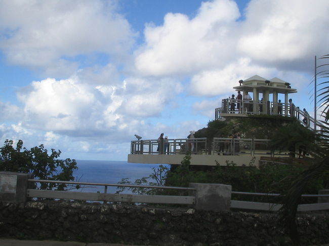 【観光バスに乗る】<br />2日目はツアーの無料オプションであるバスツアー「ボニータ号」に乗車。<br />自分たちで行くにはちょっと面倒な観光スポットに連れて行ってくれる便利なツアーでした。<br />行き先は、恋人岬、マイクロネシアモール、フィッシュアイマリンパーク、ラッテストーン公園、スペイン広場、DFSギャラリア。<br />9時〜13時まで、効率よく過ごすことができました。<br /><br />最初の目的地、恋人岬では、私たちが集合時間より少し早くバスにのり込んだとたんに、猛烈なスコールが襲来！<br />グアムのスコール、こんなにすごいとは思いませんでした。<br />雨期なのでカサは持っていたものの、あんな雨に打たれたらソッコー風邪っぴきです。<br />ウチの息子はなかなかの晴れ男かもしれません。<br /><br /><br />＊写真／恋人岬。展望台は別料金で@3ドル。入場するやいなや写真を撮られ、あとで押し売りされるのがなんだか日本的でした。。