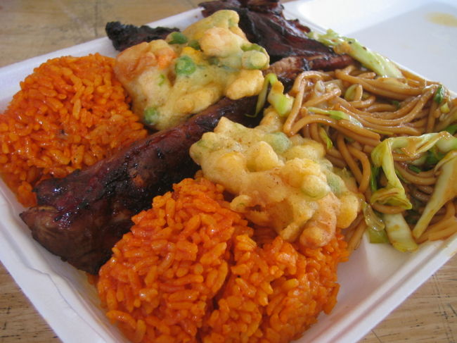 【寂し過ぎたチャモロビレッジ】<br />そして3日目。<br />今日は早くから張り切って、少し遠方のチャモロビレッジに足を運ぶことにしました。<br />先住民族チャモロ人の文化に触れられる場所で、水曜の夜にはナイトマーケットで賑わうのだそうです。<br />ここの工房で作っているチョコはとても美味しいとか。<br /><br />しかし、行ってみたら朝早いせいなのかなんなのか、店はほとんどクローズド。<br />やっているのは屋台のごはん屋さんだけ。<br />客もほとんどいません。<br /><br />でも、いくら早いっていったって、ガイドブックに書いてある営業時間の9時はとっくに過ぎてます。<br />バスを乗り継いでここまで来たのに、なんなんだ！！<br />しょうがないので、朝ごはんだけ食べることにしました。<br /><br />ここでは伝統的なチャモロ料理が味わえます。<br />私たちはいくつかある店の中から、デリっぽい雰囲気で料理が見えるお店を選び、「FIESTA PLATE」というセットをオーダーしました。<br />レッドライスに、バーベキューチキン（2種類からセレクトできる）、焼きそば、かき揚げのようなものが付いてわずか6ドル。<br />しかも相当なボリュームです。<br /><br />これが、大当たり！<br />チキンは香ばしくジューシー、焼きそばやかき揚げ風のものはちょっぴりジャパニーズテイストで食べやすく、レッドライスも美味しかったです。<br />これでこの値段、満足です。<br />ここへ来たことがムダ足にならなくて、本当によかった♪<br /><br />写真／「フィエスタプレート」。どの店もだいたい同じようなメニュー構成で、基本的にはレッドライス＋1〜3品を選ぶシステムになっています。