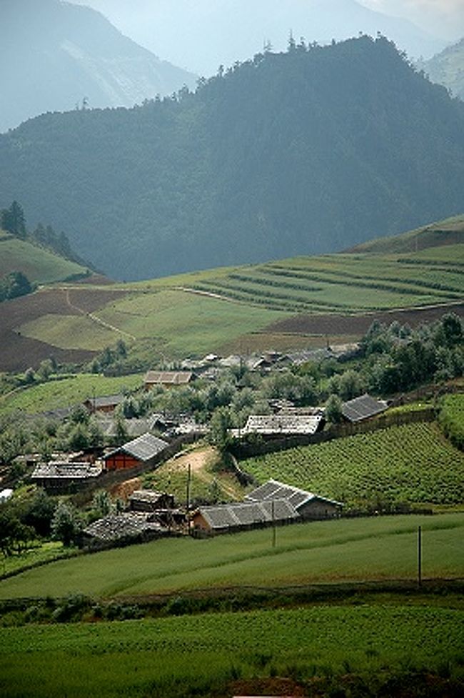 迪慶チベット族自治州の山々が何重にも折り重なって霞む朝。<br /><br />朝の光の中の集落は一見平和そうに見える。<br />でも、実際の暮らしはどうなんだろう。