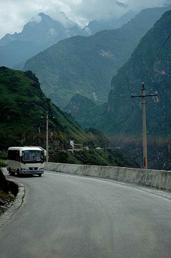≪虎跳峡鎮≫の町から迪慶チベット族自治州側の虎跳峡へ向かう道。<br />道幅は狭くなりますが、舗装は出来ていました。<br /><br /><br />お〜！　虎跳峡を挟みこむ断崖絶壁の岩山が見えてきた。<br />フロントガラスの反射が写りこんだのが惜しい！