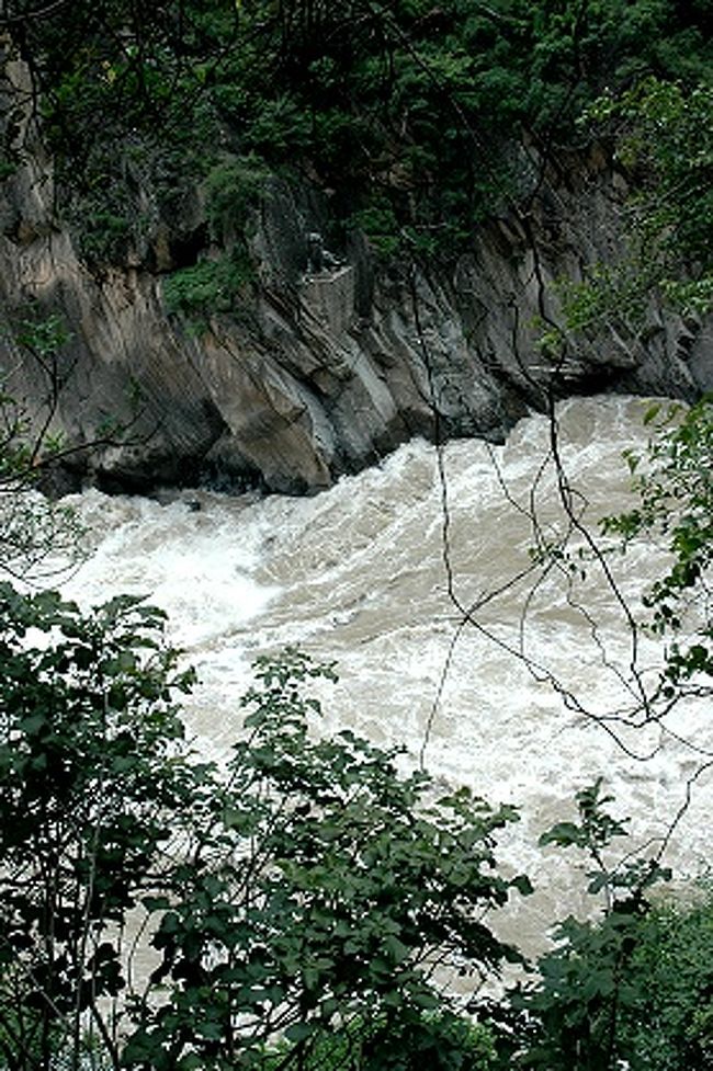 あ、ここが虎跳峡が一番狭くなった所か！<br /><br />ここの金沙江の川幅は３０ｍほどなのだそう。<br />それまではさほど強い流れとは思えなかった金沙江が突然ここで激流に変わる。<br /><br /><br />麗江市側の岩肌に虎の像が見えているのは、この峡谷の名の由来になった虎を象った物なんだろうなあ。<br />ここが虎跳石になるのかな。<br /><br />ちょっと見えにくいですが、画像中央よりちょっと上の方に、台座に据えられた虎の像があります。<br /><br />