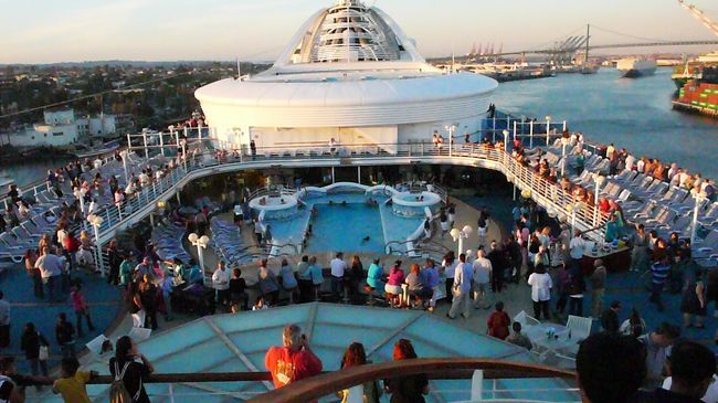デッキ１４階プールサイドで出航パーティが開かれ、多くの乗客が集まっています。
