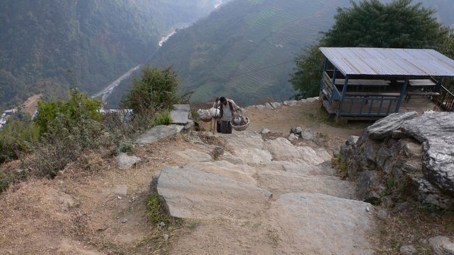 天秤棒を担ぎ石段を登る人。<br />ネパールでは天秤棒は意外に珍しく、ほとんどが肩ではなく頭（額）で重いものを支えるタイプだった。<br />