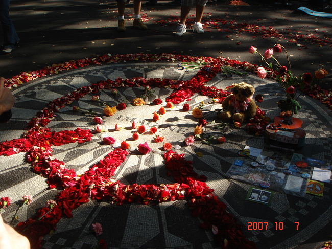 　花で飾られたストロベリー・フィールズ（Strowberry Fields）<br /><br />　中央にIMAGINEの文字。ジョン･レノンを偲び、多くの花びらと貝殻が整然と並べられていた。他に花束、ワッペン、ギター、CD、クマのぬいぐるみ等。