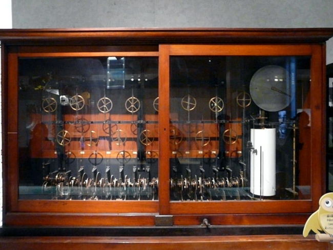 ケルビン式潮候推算機（ちょうこうすいさんき）は港湾の潮位を正確に計算で予測する機械　<br />展示されている物は、中央気象台(現、気象庁)が昭和５年から３５年まで、日本沿岸の主要地点の潮汐予測に使われていたものです