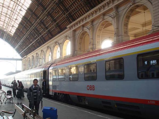 ←ウイーンへ向かう国際列車<br /><br />予約してある席には、コンパートメントの通路側の窓にカードが差し込まれていますが、無視して座っている先客をどかしたり、コンパートメントの座席シートが人数より少ないことにクレームをつけたり添乗員さんは大忙しです。<br />私たちと同じく母と娘でツアーに参加した方、友人同士の女性の６人が一緒のコンパートメントに乗り合わせることになりました。<br />ブダペストからウイーンまでの３時間の車中のおしゃべりで、年代を超えて共通項を発見した私たちはすっかり親しくなることができました。<br />同じ車両には、同じ旅行会社の関西から出発したツアーの一行が乗車していましたが、みんなのスーツケースは急ブレーキでも暴走しないように工夫して通路にぎっしり並べられていました。<br />国際列車なので、ハンガリー国内はハンガリーの乗務員、国境を越えてオーストリア領に入ればオーストリアの乗務員という決まりです。運転技術にお国柄が反映されるのか、オーストリアに入ってからは急ブレーキもなくなめらかな運転に感じました。<br />車窓から見える景色は単調な田園風景が続くだけで写真に撮りたいような風景には会いませんでした。<br />国境付近では写真撮影は禁止といわれ、少し緊張しましたが、一時停止した国境でのパスポートチェックも、私たちはツアーなのでごく簡単に顔写真をチェックされただけでした。<br /><br />