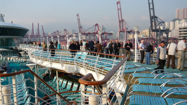 大型クレーンが立ち並ぶ出航風景を見る乗客達。<br />寒いので人々は部屋や展望ラウンジから眺めていました。