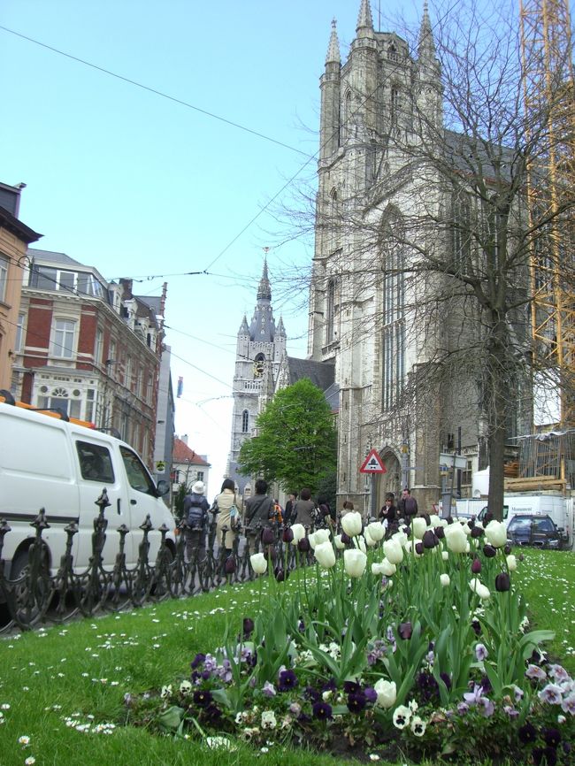 ゲント到着。バス降り場から市街地へとしばし歩く。お天気が回復して綺麗な青空が広がったせいもあってか、古いながらに明るくてイキイキとした街と直感。チューリップの咲く広場の向こうに聖堂と鐘楼が見えてきました。<br />