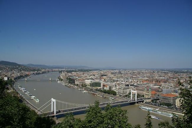 朝７時半に目覚める。。。 <br />そこはハンガリーの首都ブタペストにある日本人が経営するアンダンテ・ホステル。。。 <br />１泊１４€と少し高いが、マンガもDVDもたくさんあり、ランドリーもネットもキッチンも無料で使い放題という旅行者にはいたせりつくせりのところなので、そこに３泊した。。。 <br />予約せずに行ったので初めはフルで泊まれないと言われるが、次を探すのも億劫だったので、床でもソファーでもいいのでと言うと、何とかスペース作ってくれて簡易ベットを用意してくれた。。。 <br />ブタペストは予想外に大きい街で観光客も山のようにいた。。。 <br />その宿にも日本人だけで２０人近くはいるのだから・・・ <br />ハンガリーは温泉も有名で日本人としてはここはひとつ入っておかねばと行くが、日本のものとは違って温水プールと言ったほうがいい感じの施設だった。。。 <br />目覚めた後朝食を済ませ、８時半にチェックアウトし、ブタペスト東駅に歩いていく。。。 <br />９時半のスロヴァキアの首都ブラチスラヴァ行きの列車に乗り込む。。。 <br />郊外に来ると田園風景が車窓に広がり、心地よい時間が流れていく。。。 <br /><br />写真：ブタペスト市内とドナウ川 <br />