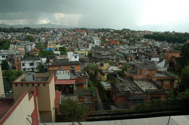 ホテルの窓からの景色です。特にこれといったランドマークはありませんが、なんとなく霞んでいます。盆地という地形に、クルマの排気ガスと乾いた空気に混じる埃が常に舞っている感じです。ちなみに窓は開きません。<br />よく見ると、あちこちでビルの屋上から子供たちが凧を揚げています。<br />ネパールって凧好き？