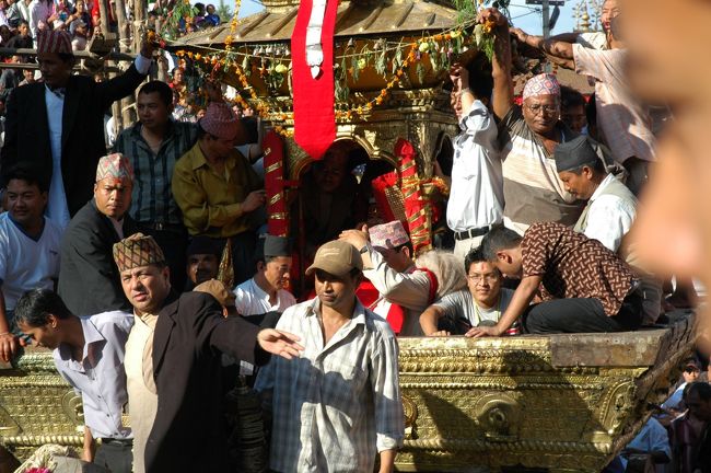 キターッ！。何がなんだかわかりませんが、大観衆のどよめきのなかに、山車が3台現われて、あっというまに目の前を通り過ぎました。あとから聞いた話しでは、生き神「クマリ」と言うのは3名いて、ネワール仏教徒の僧侶サキャの中から美しくけがれのない利発な少女から2名が選ばれ、もう1名は男の子から選ばれるそうです（オカマ？）。<br />「クマリ」は神としての振る舞いを教え込まれ、最強の女神として人々に敬われ、国王さえも膝まづかせるのだとか。<br />普段はこの広場にあるクマリの館に住んでいるのですが、年に一度のこのお祭りには山車に乗って人びとの前に姿を現わすのです。<br />走り去る山車をなんとか撮影しました。陰になってわかりにくいのですが、山車の中で大人達に守られている少女、これが「生き神クマリ」です。<br />