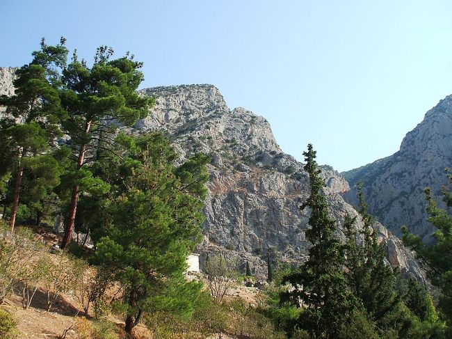 伝説によれば、この地にはガイアの息子である蛇身のピュトンが棲んでいたが、アポロンがやってきてピュトンを殺し、ガイアの予言の力を自分のものとしたという。写真：デルフィ遺跡の背後に迫るパルナッソス連山