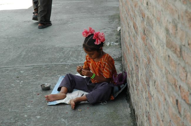カトマンズの目抜き通りで、ひとり遊びをする少女。<br />こうした風景は、そこらじゅうで見られます。<br />中には、足を怪我して歩けないヒトや、乳飲み子を抱えたお母さん達が、<br />歩いている観光客に物乞いをしています。<br />まだ10歳にもなっていない子供たちが、親からも離れ、こうして毎日を過ごしている<br />のかと思うと、とても悲しいです。