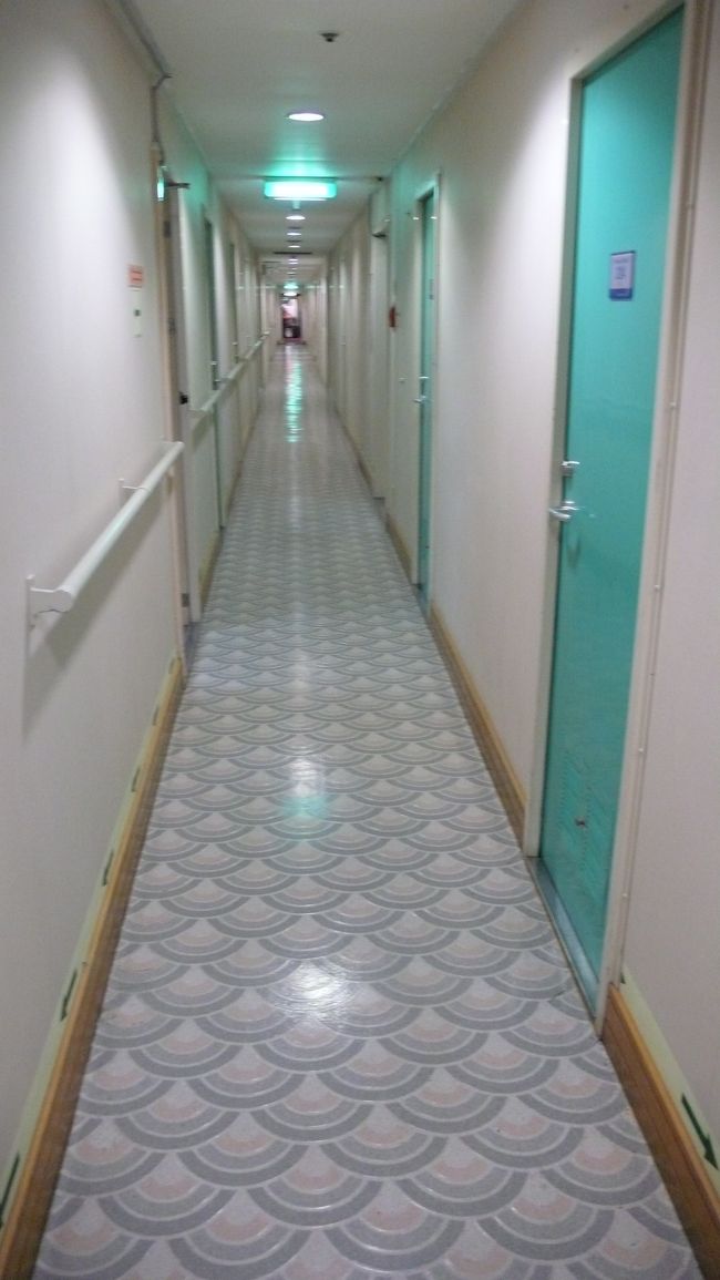 ２階Ａデッキの廊下です。<br /><br />１２３号の部屋は奥から３番目、この階は医務室が後方に有り、その他はすべて客室です。<br /><br />ロビー・案内デスク・レストラン・売店・大浴場・インターネット・デューティーフリー・カラオケルーム等すべて１階に有りますので、階段を使用しての利用となります。<br /><br />階段は１箇所しかないので、結構歩きます。<br /><br />まあ運動不足解消にはなりますけれどね。<br /><br />
