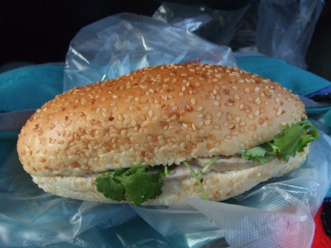 バスは、6:30にG.H.前にピックアップが迎えに来るということで6時過ぎにはフロントへ。<br />迎えが来るまでフロントのソファに座っていると、スタッフの方が1人話しかけて来てくれた。<br />彼も日本語勉強中ってことで、日本語でお話しました。<br />シェムリアップでここを紹介してくれたスタッフが言っていた友達っていうのは彼のことだったようです。<br />ピックアップが来るまで私の話相手になってくれました♪<br />無事、バスに乗り込み着席。<br />隣の席は、サングラスをかけたちょっと強面の現地のおじさん。こえ〜〜〜・・・。<br />早朝ということもあり、ミネラルウォーター1本と、ロールサンドが配られました。<br />これ、結構おいしかったです☆