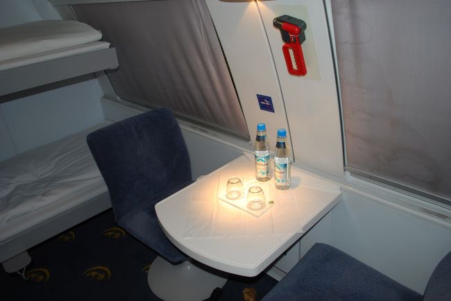 列車に乗り込むと、ちゃんと正装した爽やかなバトラーがいました。<br />チケットを見せると、「ようこそ、CNLへ。あなたがたのお部屋はこちらです」と案内してくれました。<br />こちらがお部屋です。<br />机には、ミネラルウォーターが準備されていました（無料）。