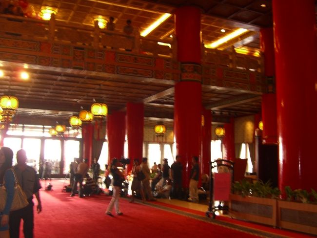 さて、次に移動するんだけど、何時だろ？「11:20」「あらー、忠烈伺の衛兵の交代式は毎時0分からなのよぅ。今からじゃ見れないねー。仕方ないから、グランドホテルに行こう♪」タクシーを拾って、地図を見せながら「グランドホテル」と言う。<br />「圓山大飯店(グランドホテル)」は、台北を代表するホテル。泊まれないなら、せめて写真だけでも・・と物見遊山ww。<br />タクシーがホテルの敷地に入ると、何だか物々しい雰囲気。警官がたくさんいる。<br />「何かあるのかなぁ？」「いやー、これくらいのホテルだと、そんなもんだろ」<br />ホテルの玄関に乗りつけ、ロビーに入ると、やはり「あー！TVカメラだぁー！」<br />(〃▽〃)ｷｬｰ♪　誰か泊まってるんだわっ！誰かしらっ？！誰なのっ！<br />「きゃー！知りたい・知りたい。誰かに聞いて来ていい？」「いいよー」<br />私は、広いロビーをうろうろ・・。フロントで聞こうかと思うけど、忙しそうだし・・・。あ、あっちでは結婚式だな。みんなキレイな格好してるよ。