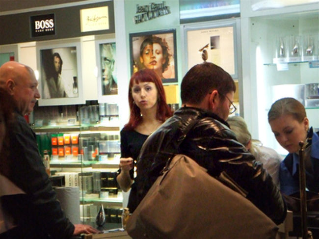 コスメ売り場の店員さん。<br /><br />ロシアにはキュートな赤い髪の人が多いです。<br />全く違和感ないのがうらやましいですね。<br />こわーい店員さんが多い中　この店員さんの態度は割りと普通でした。<br />やっぱり笑ってませんでしたが。<br /><br />この売り場は　店舗というより通路に露店みたいな形で出ていました。<br /><br />余談ですが　私も髪をこんな色にしたことありますが<br />「ビジュアル系？」と言われ、即　色を落としに行きました…。 