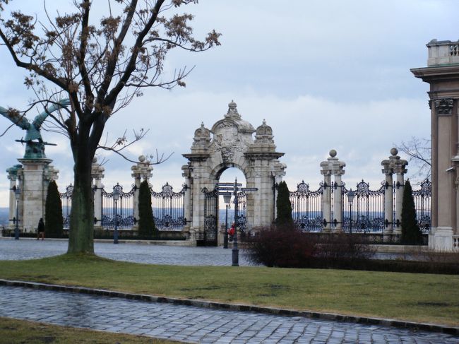 王宮奥の庭園の入り口。<br />美しい門と柵、鷲の彫刻と並んでいるが、そのままでは退屈なので、右の建物を少しと手前の木をいれて奥行きを構成してみました。肉眼では門にもっとスケールがありますが、手前まで引いたせいでこじんまりしています。<br />ここも雨が似合います。