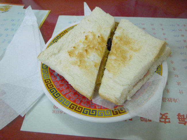 奥でおじいがゆるゆると作ってくれた、<br />公治がテーブルに。<br />まだ閉店時間まで余裕はあるのに、<br />いきなり床をモップで拭き始めたおばさん…。<br /><br />そういうのも含め、全て香港の良さ。<br />あー香港にいるんだという思いを<br />何度も噛み締めつつ、<br />公治を食べる。<br /><br />大量の油で揚げたような卵・ハム・<br />ランチョンミート・おまけにチャーシウまで<br />挟まっていた、スペシャルサンドでした。<br />(美味しい！)<br /><br />食パンの耳が少し残っているのもご愛嬌。<br /><br />中華なお皿にも、そそられます。