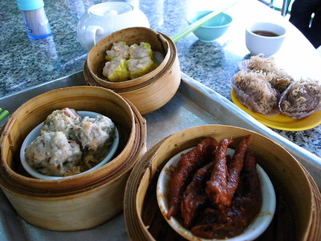 ミニバス80番の終点で降りる。<br />(…っていうか、ほぼ全員がここで降りた)。<br /><br />ここから、どう目指す飲茶店｢端記茶楼｣へ<br />行くのかわからず、坂を下りてしまうが、<br />しばらく行ってもないので、バス停まで<br />引き返す。<br /><br />バス停を降りて、来た進行方向に数メートル進むと、<br />別の飲茶店に入るような、<br />小さな階段があり、そこを降りて、<br />実際別の飲茶店のお店の敷地に半分入りながら<br />進むと、目指す｢端記茶楼｣が左に見えた。<br /><br />1Fは席が埋まっているような埋まってないような<br />変な混み方で、おじいが1人でいるテーブルに行き、<br />｢空いてる？｣とジェスチャーで聞くも、<br />｢ない｣との答え。<br /><br />日本人なんて1人もいないような地元100％の環境に<br />ちょっとびびって、(でもここまで来たし！)<br />2Fへの階段を上がる。<br /><br />2Fは2Fで、常連客らしい鳥かご持参のおじいが<br />いっぱい。マージャンをしている人もいる。<br /><br />あちこち見たあと、真ん中のテーブルに空き席を<br />見つけ、席を確保。<br /><br />まだで安心できないのは、ここがセルフの飲茶店だから。<br />まずは、お茶コーナーに行って、茶瓶をお湯で温め、<br />ポーレイ茶葉を茶瓶に入れる。<br /><br />すごく大きい茶瓶だったので、葉の量がわからず、<br />｢見せて｣と日本語で隣のおじさんに話しかけ、<br />おじさんのポーレイ量をチェック、同じ量になるよう<br />茶葉を増やす。<br />お客のおじさんたちは、<br />何を言っているかわからないけど、親切だった。<br /><br />チャイラン氏の本によると、<br />おいしい茶葉を持ち込んで飲んでもいいらしい。<br />ここのお湯は、近くの大帽山の湧き水を使って<br />沸かしているらしく、お茶もおいしく感じられた。<br /><br />その後は、香港名物、洗杯。<br />使う箸や食器を、お茶淹れ場の熱湯で洗う。<br />まず、一度テーブルにお茶セットを持ってきて、<br />その後は、１Fの点心コーナーへ。<br /><br />鶏の足の煮込み、シュウマイ、タロイモコロッケ、<br />などなどを取ってくる。