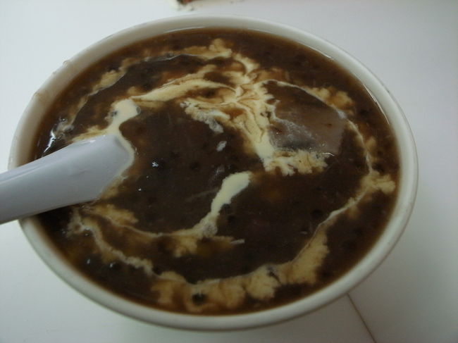 旺角から油麻地まで、街をぶらぶらしながら<br />歩いて見て回る。<br /><br />油麻地駅近くの廟街で、いつもなら<br />レトロ喫茶｢美都餐室｣に入るんだけど、<br />http://www.openrice.com/restaurant/sr2.htm?shopid=2310<br />今回は向かいにあるおしるこの店、<br />｢源記じゃあちゃあ(←漢字なし)｣に初めて入ってみた。<br />http://www.openrice.com/restaurant/sr2.htm?shopid=11869<br /><br />おしるこ(？)は、14ドル。<br />｢Hot？Cold？｣と店員さんに聞かれ、<br />あわてて｢いっげ(熱いの)｣と答えて、<br />(冷たいのにすればよかった〜)と、<br />よくわからない結果になってしまった。<br /><br />この日は結構むし熱くて、<br />熱いおしるこは、かなり食べるの大変だった…。<br />(さっき、許留山でもジュース飲んだしね…)<br /><br />とろみのある汁に、<br />ココナッツクリームがかかっていて、<br />中にはいろんな種類の豆がいっぱい。<br /><br />メニューも他にいろいろあったけど、<br />店名にもなっている｢じゃあちゃあ｣が名物らしい。