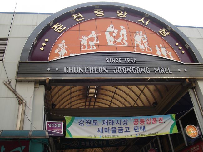 春川明洞の通りの中央にはクリスマスツリーのような街路樹が並んでいます。ドラマで使われたのはどこだろうと探していたら、中央市場まで来てしまいました。<br /><br />この中にはユジンのお母さんのお店や、ユジンが酔っぱらいにからまれた場所などがあるそうですが、時間がないため探せずUターンします。