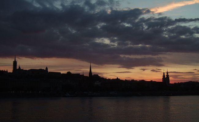 　夕食後、城バスでモスクワ広場に下り、メトロＭ２で国会議事堂前に抜けました。そこからドナウ河畔東岸（ペスト側）をぶらぶらとくさり橋まで散歩。<br />　時刻は午後８時過ぎで、ドナウ川の向こうに、夕焼けを背景に改修中のマチャーシュ教会の尖塔などが黒いシルエットで浮かび上がっていました。