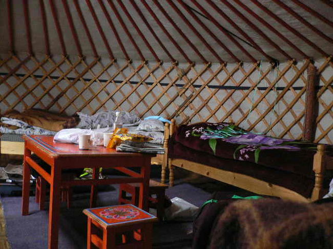 ゲルの内部です。結構広く快適です。中央の屋根には穴が空いていて　ポッカリと空が見えます。夜には穴を閉じて寝ます。オレンジの机と椅子はきれいなペイントがされています。