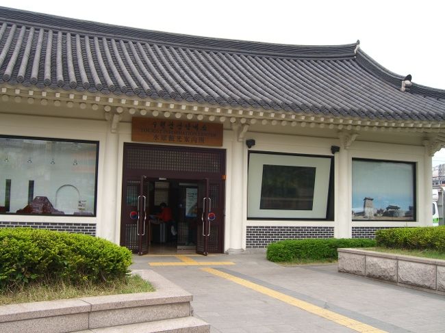 「観光案内所に行きたいけど、さてどこだろう？」改札を出て、何気に右に歩いて、駅の階段を下りる。地図看板を見つけて、案内所の場所発見。左に少し歩くと、あった。<br />中で「民族村」と聞くと、「隣」と言われ、右隅の係りの人にもう一度言う。<br />無料のシャトルバスが隣の駐車場に来るので、待つように・・と、チケットを貰う。<br />外でぽーーっと待っていると、大きなバスが来て、並んでた人が乗り込む。我々もチケットを見せて、乗る。