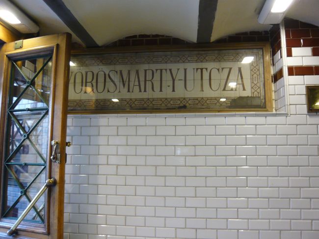 　オペラ座からほんの１駅、２駅程度です。ヴィレシマルティ・ウッツァ。<br />　Utcaというのが”通り”という意味ですが‥‥ここにはUtczaと書いてありますね。むかしのスペルなのかなあ？　<br />　ここはプラットフォームです。左側に扉が見えますね。そして、妙に明るいですね。<br />　そうです。大陸最古なだけあって、えらく浅い場所にあるのです。マジで、地下一階、という程度の深さです。