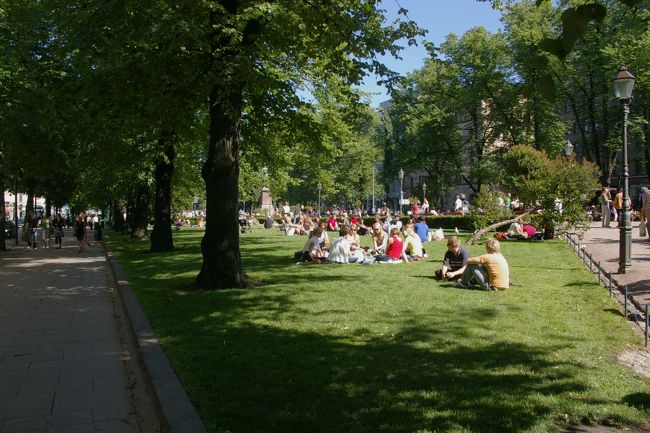 公園で日向ぼっこをしながら談笑する人達。