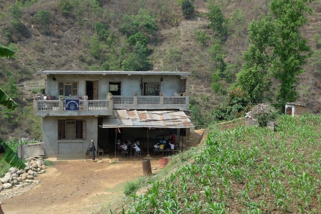 正直言うと私はRs250のバスでOKな人。でも今回はRs500にしといてよかったー。というのも順調に走り続けドライブインでのランチも終わって、あと2時間くらいで到着か、という時にバスがいきなり停止。<br /><br />乗り合わせたネパリ達がみんなバスを降りていくので窓から外を覗くと大渋滞で全く動く気配がない。前の車の人たちも車から降りてタバコ吸ったり、日陰で昼寝してる人まで！<br /><br />しばらくして入ってきた情報によると交通事故で道路が完全閉鎖。マジですか!?<br /><br />写真は停車していた場所から見えた小学校。