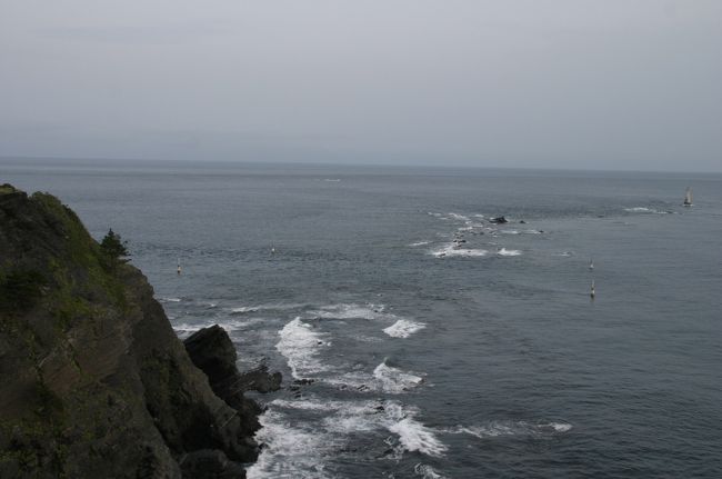 豆酘崎の灯台は岩礁が続き、その先に海の中にそびえるように灯台が建っています。<br />