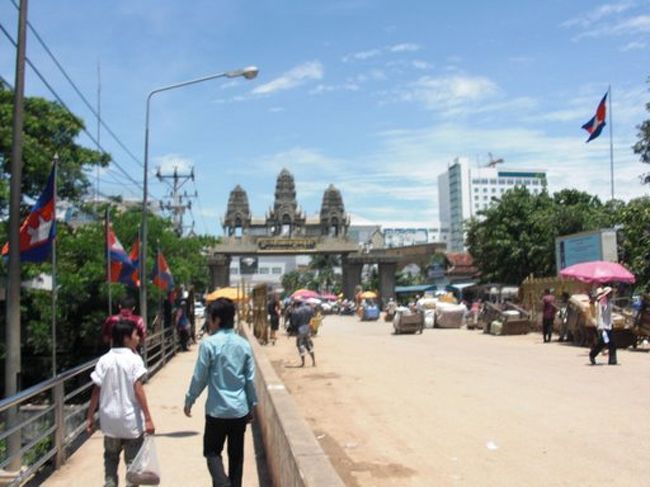 アンコールワットを模した<br />国境（カンボジア側イミグレーション）<br /><br /><br />＊＊＊＊＊＊＊＊＊＊＊＊<br /><br />前回からの続き。詳しくはバンコク〜上海　バックパッカー大学三年の夏。　タイ編を参照してください。<br /><br /><br />CHAGEが運転するトゥクトゥクに揺られること１５分。<br /><br />国境前に着いた。<br /><br />ちょうど昼時で<br />適当な食堂に入り、まずいチャーハンを食す。<br /><br /><br />すると、真っ赤なシャツを着た男に話しかけられる。<br />タイ人よりも肌が明らかに黒い。<br /><br />人種の違いを感じる。<br />生まれて初めてみるカンボジア人だ。<br /><br /><br />バスの客引きである。<br /><br />国境からアンコールワットがあるシェムリアップまでの<br />バスを手配するひとで、<br />料金は24USドル。<br /><br />高い気がするし、断りたいけど<br />ずっと付きまとってくるし、<br /><br />なんかいろいろ親切にしてくれる。<br /><br />というか謙った態度に申し訳ない気分になる。