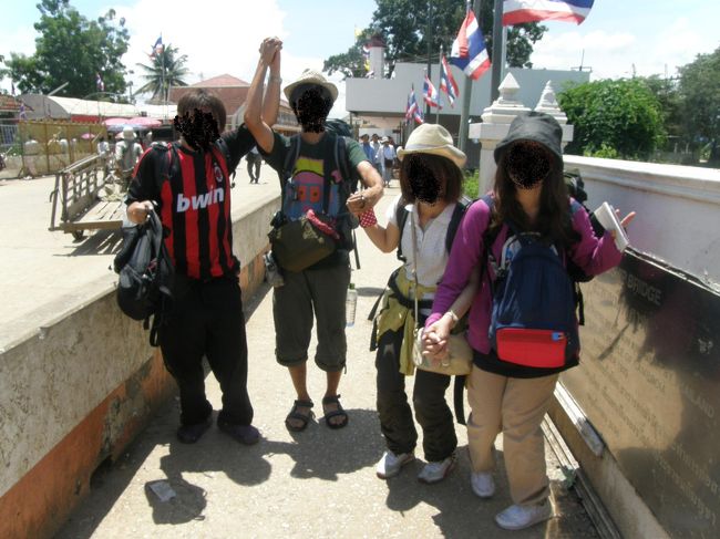 タイとカンボジアを結ぶ<br />“友好橋”で全員集合！！<br /><br />見せられないのが残念だが、みんないい笑顔をしてる。<br /><br />撮影者：赤シャツカンボジア人。<br /><br />＊＊＊＊＊＊＊＊＊＊＊＊＊<br /><br />赤シャツカンボジア人（以下赤）<br />に率いられるままに、入国手続きをする。<br /><br />しかし、イミグレーションに慣れていなくて<br />俺とKは入国カードを赤に指示されながら事務所のはずれのベンチで書く。<br />もちろん外国人バックパッカーの軽蔑の視線を浴びながらである。<br /><br />すると女二人が、日本人のイケメンバックパッカー2人組にナンパされている。<br /><br />面白いから眺めていよう。<br /><br /><br />わくわく