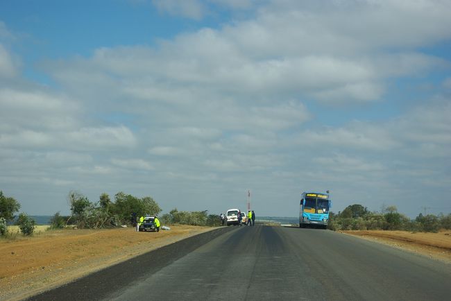 検問中。<br />いろんな所で検問をやっていました。<br />私たちの車も旅行中に２回止められました。<br />ガイドさんいわく、「運転免許証を更新しない人が多いから、それをチェックしてる。いつもの事だよ〜」とのこと。<br />免許証も見せてくれました！<br />厚紙を３つ折りにしたものに写真が貼ってあって、<br />いろんなスタンプが押されていました。<br />インドの免許証はプラスチックのカード式なのに、写真がちっちゃくて不鮮明でしたし、いろんな国の免許証を見せてもらうとおもしろいです。<br />警察の人は、車を停止させて、めっちゃニラんで車をチェック。フロントガラスに張られてる、ガイドのライセンス見たいなのをみたりしてました。ガイド兼ドライバーさんが車から降りて、車の後ろの方で２人でなんかしゃべった後は、警察の人、ニコニコして「ジャンボ〜！」とかって言ってます。ガイドさんには聞かなかったけど、ディベートでも渡したのかな？