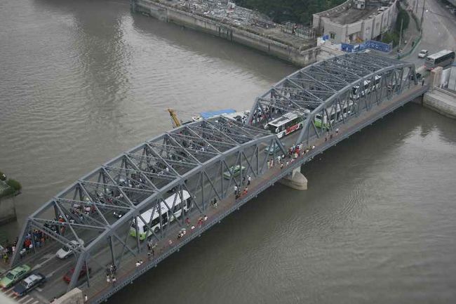 眼下の橋から（おそらく）皆既日食を見ようと集まった人々。<br /><br />数枚写真を撮っていると、雨がボツボツそして、ザーザー降りだしました。<br />わたしは日食観測を諦め、ホテルのウィンドーショッピングでもすることにしました。１Fのお店で店員さんとお喋りしながら、ふと気がつくと、外が真っ暗になっていました。おそらく皆既の状態にに入ったのでしょう。<br />店員さんは日食（リー　ジー）は興味ないといっていましたが、夜の8時頃の様子をみて、二人で「ワー」とはしゃいでしまいました。<br /><br />弟からもらった日食グラスは結局、買ったままの状態で、とうとうビニル袋から出さずしまいでした。次回の日食までこのまま押し入れに閉まっておこうと思います。<br /><br />上海の旅はこれでおしまいです。夕方の便で上海から桂林へ。その機内で入手した夕刊に日食の記事が各誌一面で出ていました。面白いことに、わたしが滞在したホテル（上海大廈）の屋上テラスからの風景写真（完全予約で入場できなかったところ）が掲載されていました。<br /><br />そんなこんなの上海旅行でした。<br />（桂林へ続く）