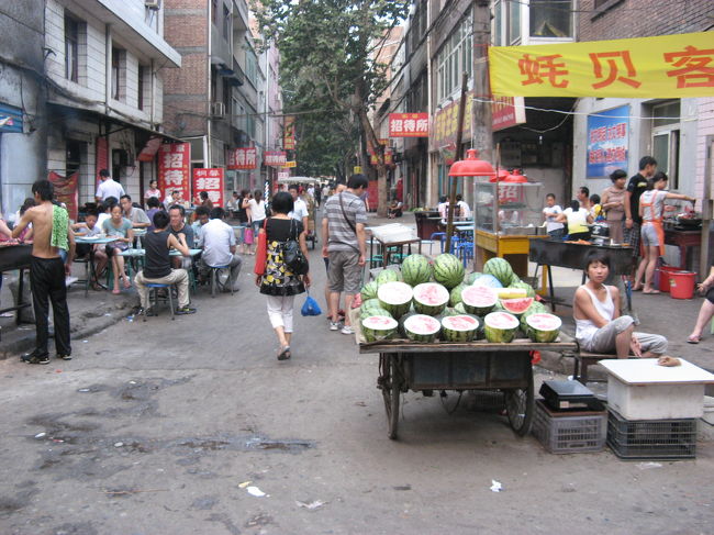 この辺りのスイカは、真ん丸ではなくて、長細い楕円のような形です。<br /><br />道の端にはテーブルが置かれ、人々が食事をしていました。