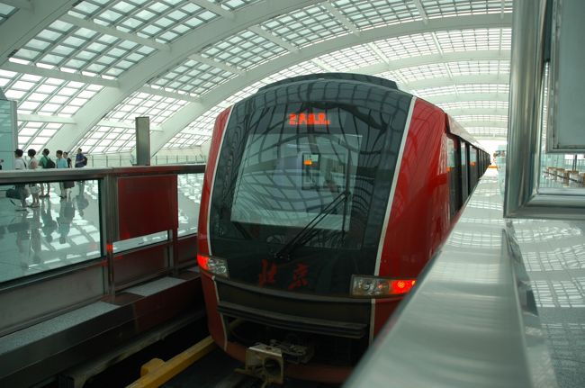 成田〜北京は約3時間半の飛行です。水平飛行が2時間半くらいなので、食事して映画一本見るのにはちょうどいい時間ですね。<br />着陸態勢のアナウンスがあってから、窓の外を見ると雲の中の雰囲気だったのですが、いきなりドスンと着陸してしまいました。<br />なんと、雲のなかかと思っていたらかなり霞んでいて、地面が近づいていたのがわからなかったくらいです。<br />初めての北京空港は、さすがに新しくて綺麗。第三ターミナルまであって、その広さにもびっくり。やっぱりオリンピックの影響は大きいのでしょうか。<br />空港から市内へは、こちらもオリンピック時に合わせて作られた直通快速電車に乗ることに。<br />新しい乗り物を見ると乗らずにいられない性質でして。。。