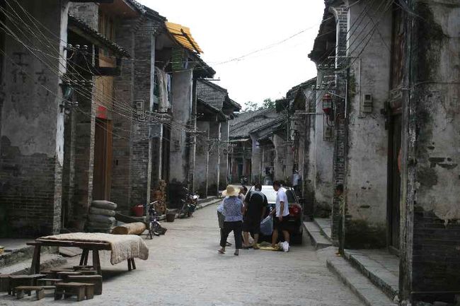 興坪鎮に着きました。<br />古い家並みには不似合いな車両ですが…<br />桂林や陽朔では、<br />新しい道路がどんどん発達しています。<br /><br />以前は桂林市内が<br />このような景色だったのが<br />道路が伸びてゆくにつれて、<br />近代的な町並みに変わってきたそうです。<br /><br /><br />ふと、「古い舞台が見学できる」<br />と声をかけられました。<br /><br />「無料です」というのに、<br />呼び込みのお姉さんの態度がとても親切そうなので<br />ガイドさんの表情を伺うと<br />「…」<br />「入ってみよう」と私が言って中へ。<br /><br />