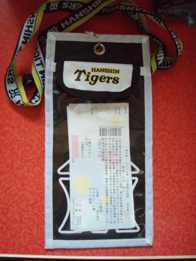 では七つ道具のうち少しをご紹介。<br />これは「チケットホルダー」です。<br /><br />プロ野球は特にそうなのですが、座席を離れて、食べ物を買いに行ったり、タバコを吸いに行って戻ってくる時に、どこの球場でもチケットの再確認をする球場が多くなってきました。<br />以前はその度に財布からまたチケットを出したりしていたのですが、食べ物を買った帰りは両手がふさがっている時が多くて非常に面倒くさいことでした。<br /><br />そこでこれを購入したのですが、正解でした。以後非常に重宝しています。