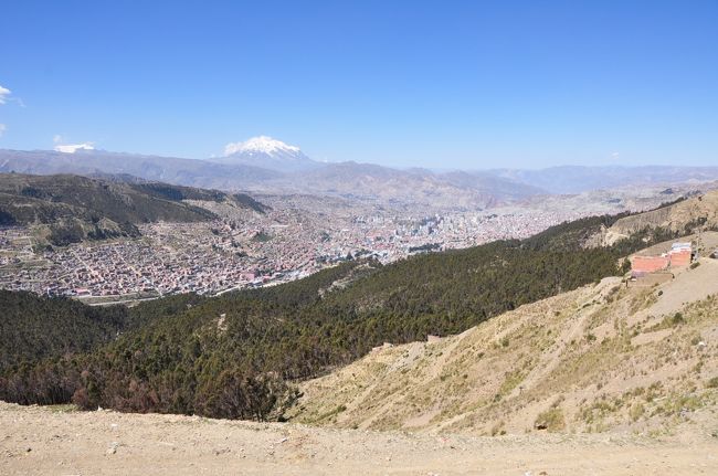 11時、装備がそろいガイドと一緒に出発。ガイドは（ボリビア人なのになぜか）フランシス、22歳。僕とフランシスを乗せた車はラパス市内を離れ、ぐんぐんと高度を上げていく。<br /><br />途中、ラパス市街を見渡す丘からパシャリ。盆地というよりもクレーターのような窪地に家々が密集しているのがよくわかる。